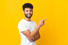 Young Moroccan Man Isolated On Yellow Background Pointing Finger To The Side