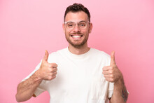 Young Brazilian Man Isolated On Pink Background With Glasses And With Thumb Up