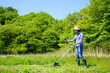 草刈り機で草刈りをする中年女性