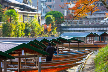 Wall Mural - Boat ride pier at Hozugawa River, boat for tourists to enjoy the autumn view along the bank of Hozu river, Arashiyama, Kyoto, Japan.