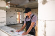 © Ольга Симонова - Construction worker engineer at construction site measures the length of window opening and brick wall with tape measure. Man in work clothes - jumpsuit and cap