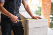 © Ольга Симонова - Construction worker at construction site measures the length of window opening and brick wall with tape measure. Cottage are made of porous concrete blocks, work clothes - jumpsuit and baseball cap