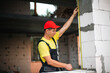 © Ольга Симонова - Construction worker at construction site measures the length of window opening and brick wall with tape measure. Cottage are made of porous concrete blocks, work clothes - jumpsuit and baseball cap
