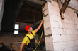 © Ольга Симонова - Construction worker at construction site measures the length of window opening and brick wall with tape measure. Cottage are made of porous concrete blocks, work clothes - jumpsuit and baseball cap