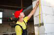 © Ольга Симонова - Construction worker at construction site measures the length of window opening and brick wall with tape measure. Cottage are made of porous concrete blocks, work clothes - jumpsuit and baseball cap