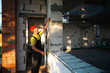 © Ольга Симонова - Construction worker at construction site measures the length of window opening and brick wall with tape measure. Cottage are made of porous concrete blocks, work clothes - jumpsuit and baseball cap