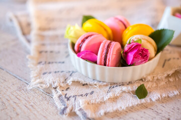 Wall Mural - Good morning. Delicious macarons desserts are served on the table in the morning for breakfast. Beautiful light still life with a rose highlight. Baking for breakfast on a light table with copy space