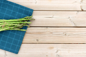 Wall Mural - Green asparagus on a wooden background. Fresh young asparagus pods. 