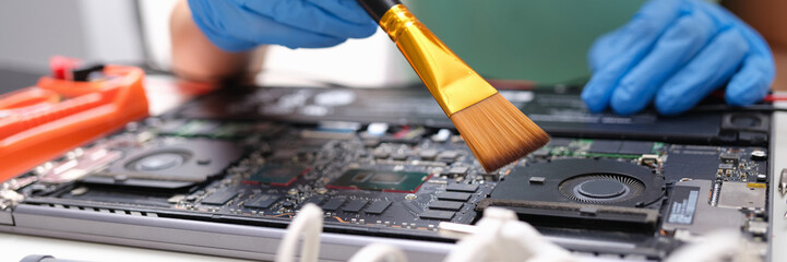 Canvas Print - Hands brush the laptop parts from dust with a brush