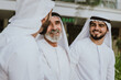 © oneinchpunch - Three business men walking in Dubai wearing traditional emirati clothes