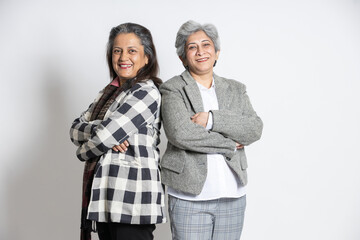 Portrait of a two confident mature senior indian businesswomen standing with his arms cross isolated on white background. successful gray-haired 60s asian lady executives manager standing.