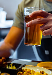 Wall Mural - man hand with glass of cold beer and plate with snacks in bar or pub