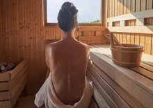 Woman With Open Back Relaxing In The Wellness Spa, Sweating In Finnish Sauna.