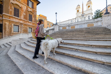 Wall Mural - Woman walks with her white dog on famous Spanish steps in Rome. Elegant woman dressed in italian old fashion style. Concept of italian lifestyle and travel