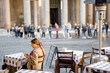 Woman sitting at outdoor cafe near famous Pantheon temple in Rome. Idea of spending time in Rome. Concept of italian lifestyle and travel