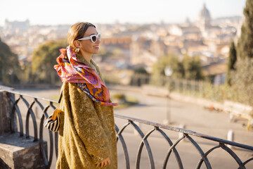 Wall Mural - Woman enjoying beautiful morning cityscape of Rome, walking in Villa Borghese Park. Old fashioned woman wearing coat with colorful shawl in hair. Concept of italian lifestyle and travel