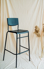 Black High Bar Stool On Beige Background Of Crumpled Fabric. A Modern Model. Comfortable Furniture For A Bar Or Restaurant. Photo Zone.