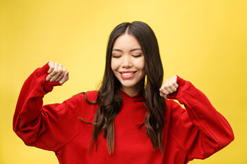 Sticker - Portrait of a happy asian woman dancing isolated over yellow background