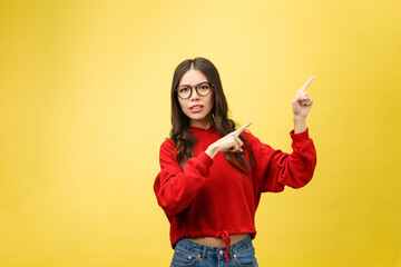 Wall Mural - Young beautiful asian woman pointing to copyspace, isolated on yellow background