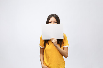 Wall Mural - surprised young girl in yellow shirt with white placard in hands isolated