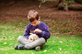 Fototapeta Dmuchawce - Hispanic boy with a rabbit in the park