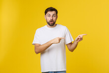 Man Pointing Showing Copy Space Isolated On Yellow Background. Casual Handsome Caucasian Young Man.