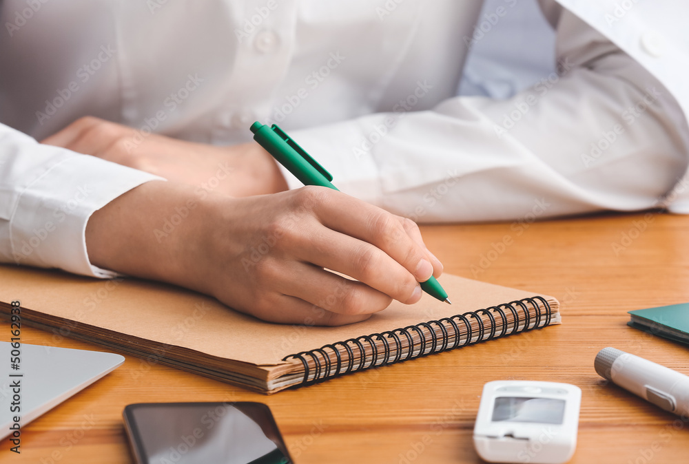 Female doctor writing in notebook at table, closeup