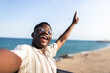© Daniel - Ecstatic African American man taking selfie at the beach during vacations. Happy, black male looking at camera.