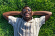 © Daniel - Top view of black man relaxing on grass. Happy black male lying on grass, smiling, enjoying life.