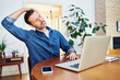 Leinwandbild Motiv Man stretching his neck while working on laptop at home