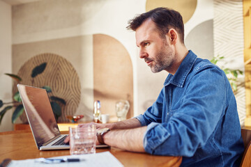 Male programmer working from home coding on laptop.