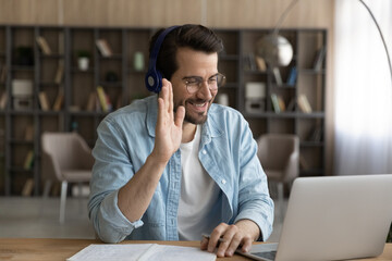 Wall Mural - got an answer. young bearded male student in headset take part in online educational event raise han