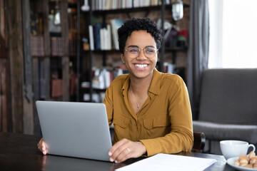 happy african woman freelancer distracted from working on laptop smile staring into distance, sit at