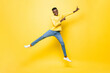 © Atstock Productions - Full length portrait of young smiling African man jumping and pointing hands up in studio yellow isolated background