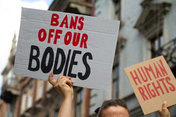 Protesters holding signs Bans Off Our Bodies and Human rights. People with placards supporting abortion rights at protest rally demonstration.