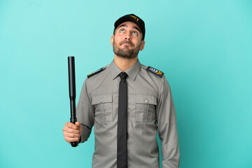 Wall Mural - Young security man isolated on blue background and looking up