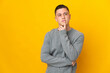 © luismolinero - Young caucasian man isolated on yellow background having doubts while looking up