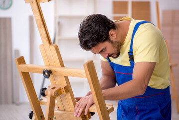 Young male repairman repairing easel at home