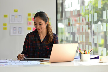 Young Asian designer working with laptop computer in creative office, Developing a New app design and User interface in a digital graphics editing software.