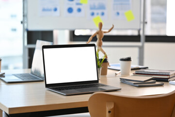 Poster - A blank white screen laptop computer setting on the wooden desk with the modern interior office decoration. Business and financial concepts.