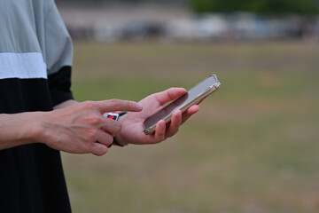 Poster - Close up male hands holding a smartphone and try to use it over an outdoor view as a background. Business and technology concepts.