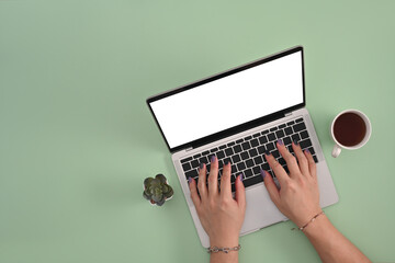Poster - Male hands with colored nails and bracelets using a laptop computer with an empty white screen between a cactus and a cup of coffee on the light green background. Flat lay composition.