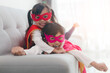 © FAMILY STOCK - happy and confident young kids playing and dressing up as superhero together in bedroom
