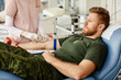 © Seventyfour - Portrait of male soldier giving blood at donor center with nurse helping, copy space