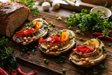 Sourdough bread open faced sandwiches with hummus, grilled zucchini and tomatoes on a rustic board, close up view. A healthy and delicious vegetarian food