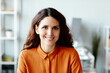 © Seventyfour - Medium close-up of charming Caucasian woman with long dark brown hear sitting in office smiling at camera