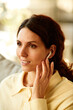 © Seventyfour - Vertical medium close-up of beautiful young adult Caucasian woman with long wavy hair having phone call using wireless earbuds