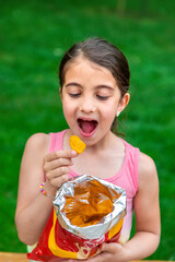 Poster - The child eats chips in the park. Selective focus.