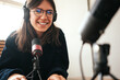 © Alex from the Rock - Handsome woman host streaming her audio podcast using microphone at small broadcast studio
