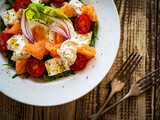 Fototapeta Kawa jest smaczna - Salmon salad - smoked salmon hard boiled eggs, white cheese and green vegetables on wooden table
